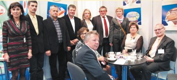 Od prawej strony przy stoliku siedzą: Helmut Doliwa, Prezes; Zofia Just, Wiceprezes oraz Członkowie Rady Nadzorczej w otoczeniu pracowników spółdzielni Czarnków (OSM)
